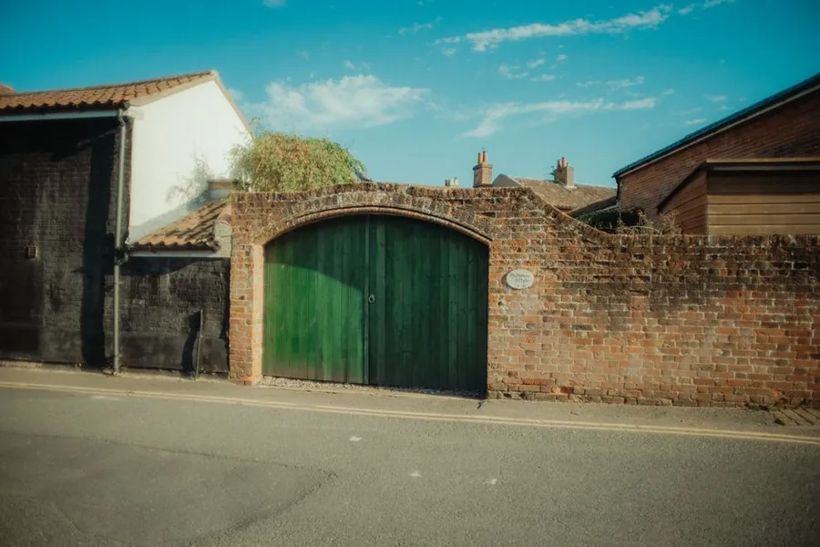 Brick pillars and boundary wall framing a pair of timber gates on an English street