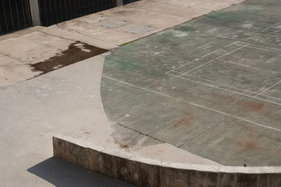 Weathered concrete surface with the colour worn flat and the sealed finish gone, the typical look of an unsealed imprinted drive