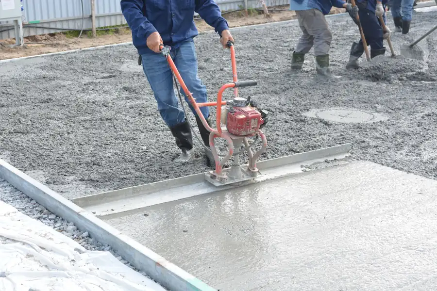 Contractors power floating a freshly poured concrete slab, the stage at which a replacement driveway base is finished