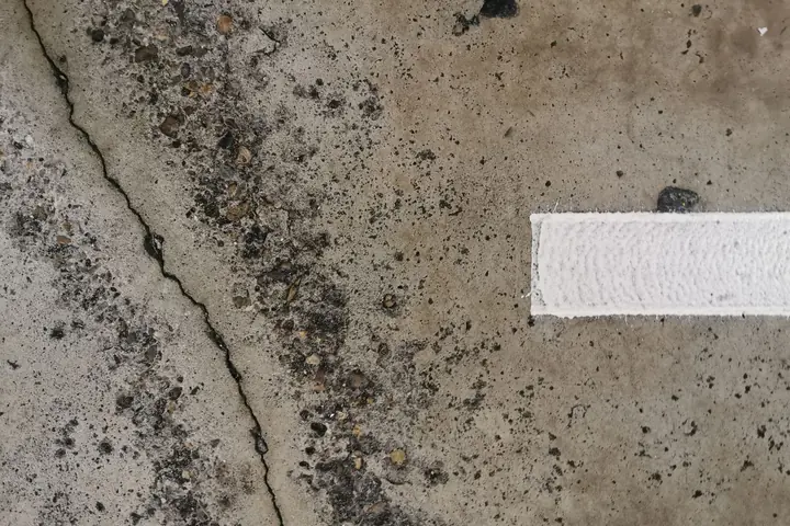 A structural crack tracking across a weathered concrete slab, the kind of movement crack that filler will not fix