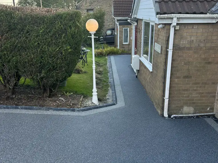 Grey resin bound driveway running down the side of a Middleton semi, finished with a dark block edge