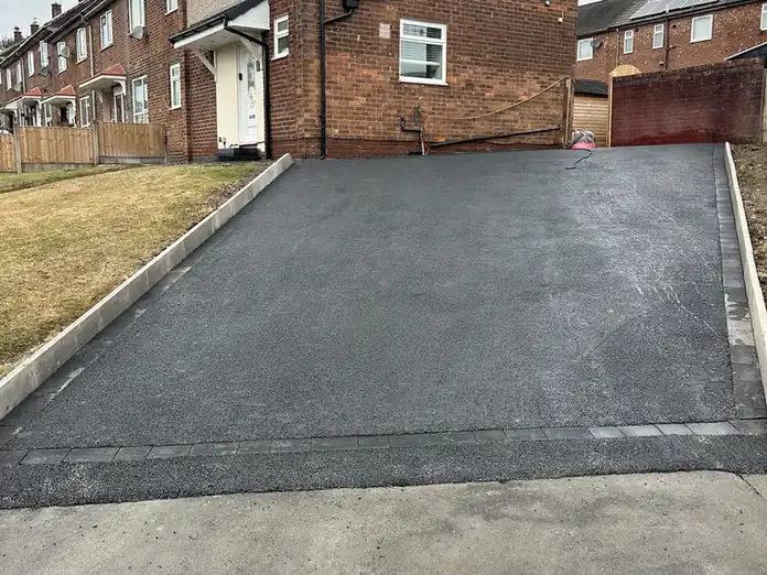 Full width tarmac driveway on an end terrace in Middleton with a block soldier course and kerb edging along the pavement